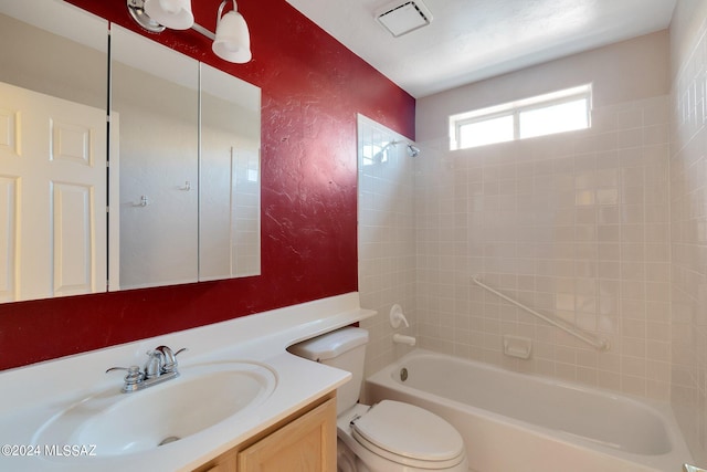 full bathroom featuring vanity, tiled shower / bath, and toilet