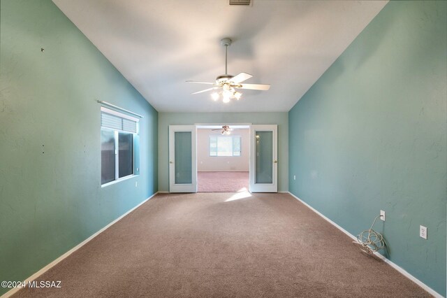 carpeted spare room with french doors, a wealth of natural light, ceiling fan, and vaulted ceiling