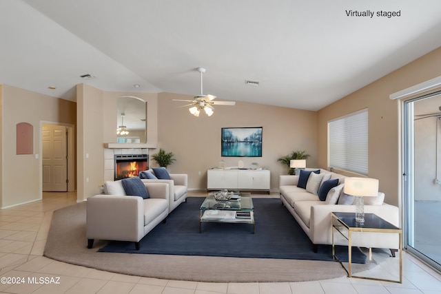 tiled living room with vaulted ceiling, a tile fireplace, and ceiling fan