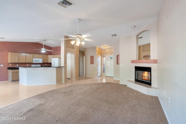 unfurnished living room with vaulted ceiling, light carpet, ceiling fan, and a fireplace