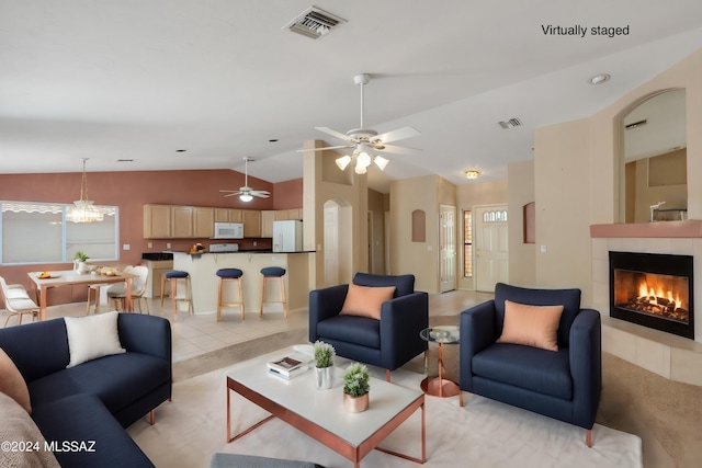 tiled living room with a tiled fireplace, vaulted ceiling, and ceiling fan