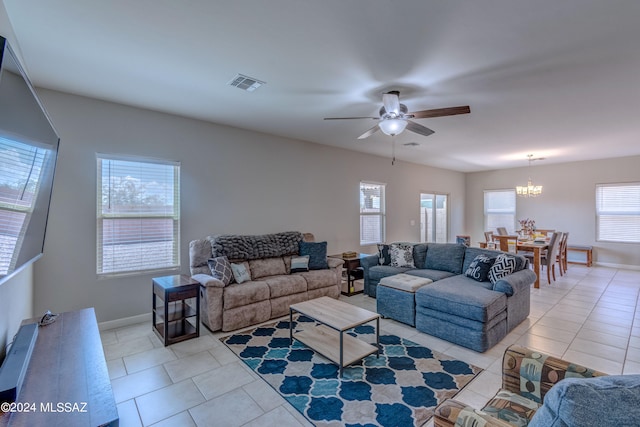 tiled living room with a wealth of natural light and ceiling fan with notable chandelier