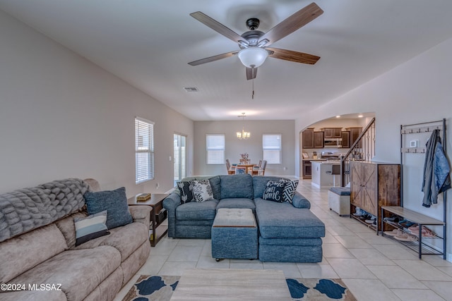 tiled living room featuring ceiling fan with notable chandelier