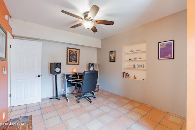 tiled office space featuring ceiling fan and built in shelves