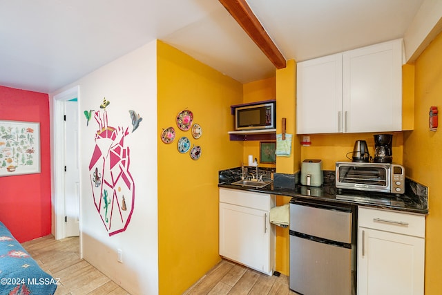 kitchen featuring stainless steel refrigerator, white cabinets, built in microwave, and sink