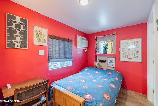 bedroom with a wall mounted air conditioner and hardwood / wood-style flooring