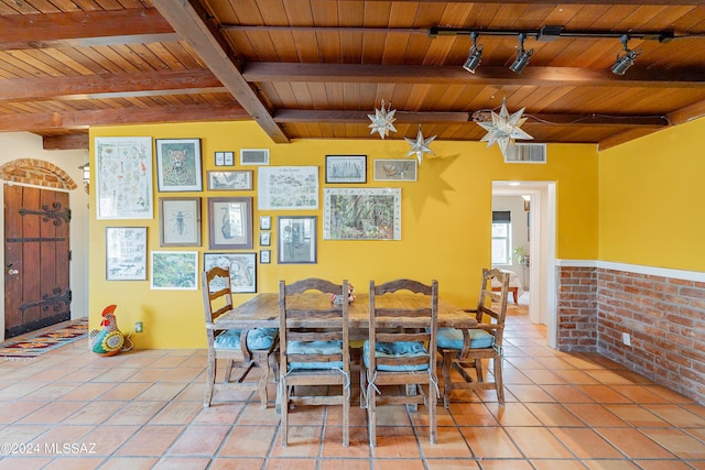 dining room featuring beamed ceiling, wood ceiling, brick wall, and rail lighting