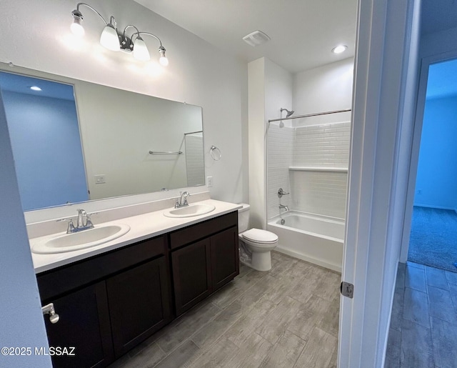 full bathroom featuring vanity, hardwood / wood-style floors, washtub / shower combination, and toilet