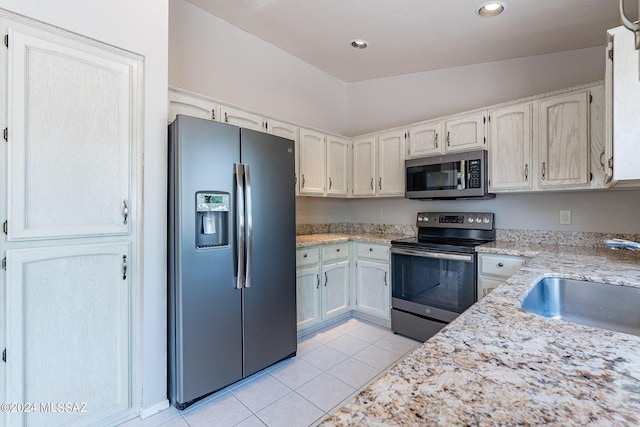 kitchen with light tile patterned flooring, appliances with stainless steel finishes, sink, and light stone counters