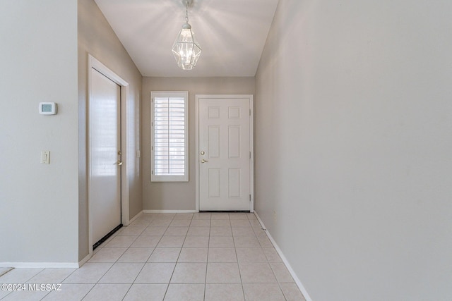 doorway to outside with an inviting chandelier and light tile patterned floors