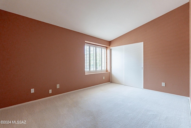 spare room featuring lofted ceiling and carpet