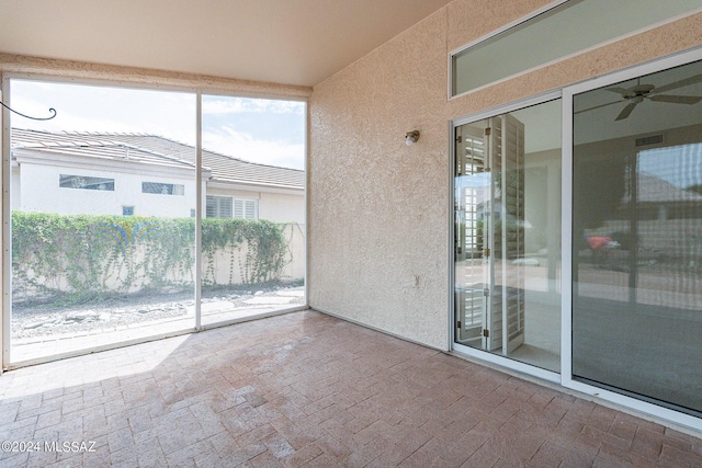 unfurnished sunroom featuring ceiling fan