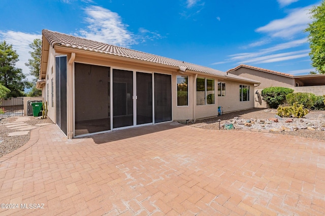 rear view of property with a sunroom and a patio