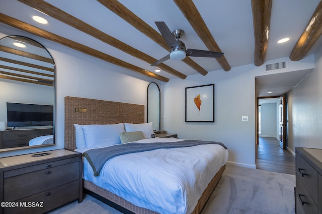 carpeted bedroom with beamed ceiling and ceiling fan