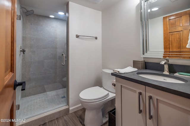 bathroom featuring wood-type flooring, toilet, vanity, and an enclosed shower