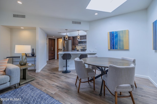 dining area featuring light hardwood / wood-style floors, sink, and a skylight