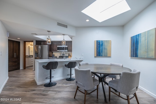 dining area featuring sink, hardwood / wood-style flooring, and a skylight