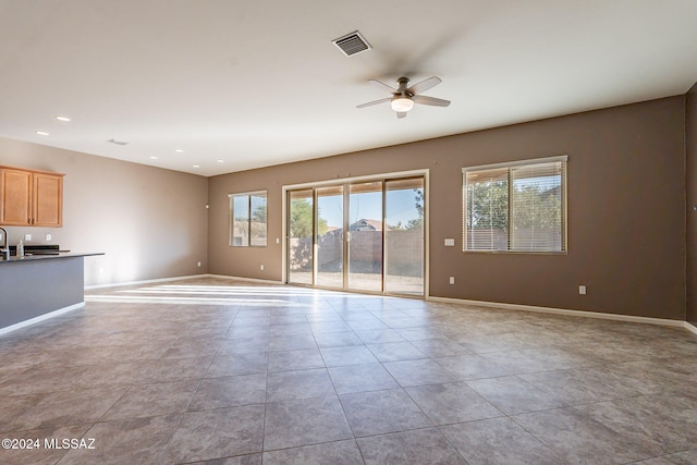 unfurnished living room featuring ceiling fan, light tile patterned floors, and plenty of natural light