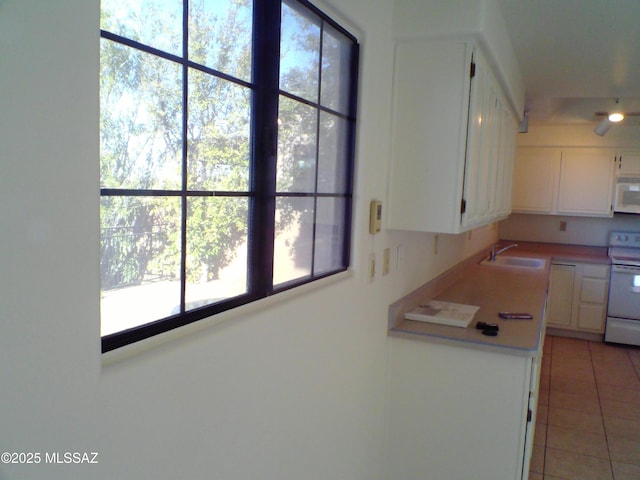 kitchen featuring light tile patterned flooring, white appliances, sink, and white cabinets