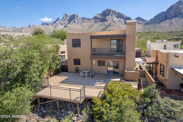 back of property with a balcony, a mountain view, and a patio