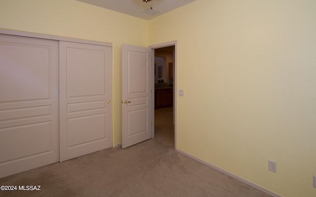 unfurnished bedroom with light carpet and a closet