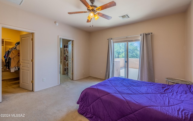 bedroom with access to outside, a spacious closet, ceiling fan, light carpet, and a closet