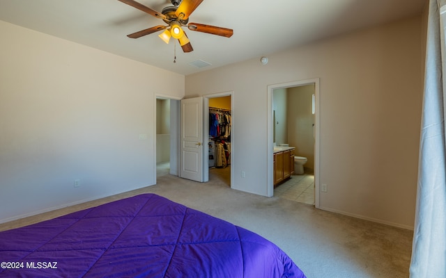 unfurnished bedroom with a closet, ceiling fan, ensuite bath, a walk in closet, and light tile patterned floors