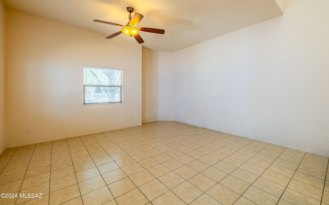 spare room featuring vaulted ceiling, light tile patterned floors, and ceiling fan