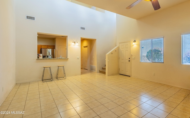 tiled spare room featuring ceiling fan and a towering ceiling