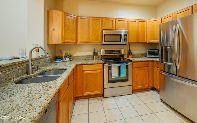 kitchen featuring sink, appliances with stainless steel finishes, light stone counters, and light tile patterned floors