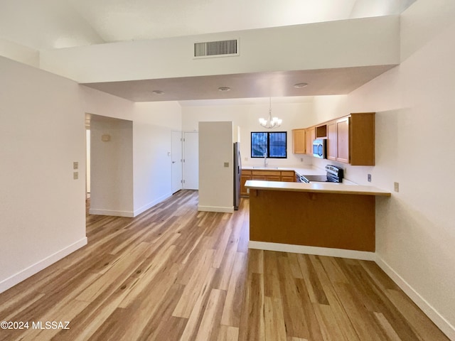 kitchen featuring kitchen peninsula, decorative light fixtures, stainless steel appliances, an inviting chandelier, and light hardwood / wood-style floors