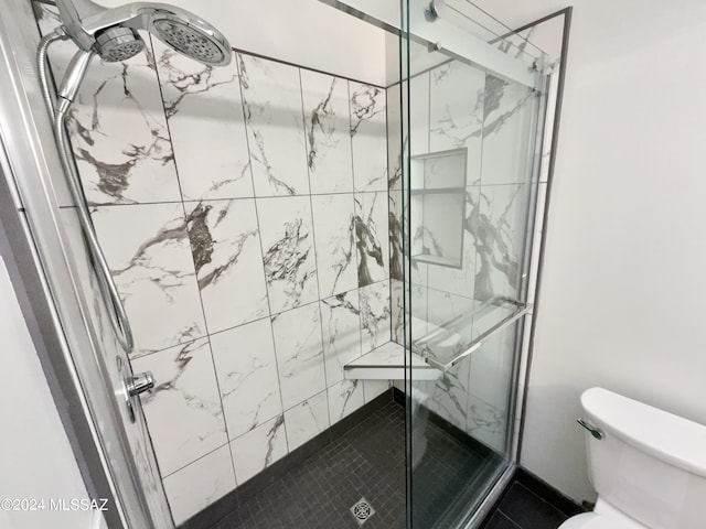 bathroom with a shower with shower door and toilet