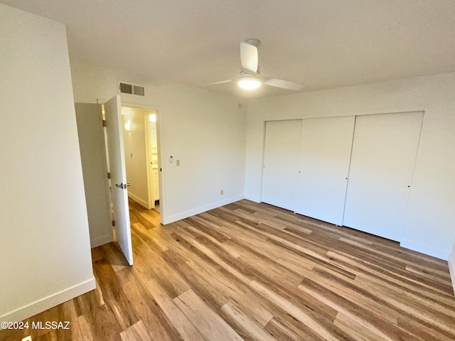 unfurnished bedroom with ceiling fan, a closet, and hardwood / wood-style floors