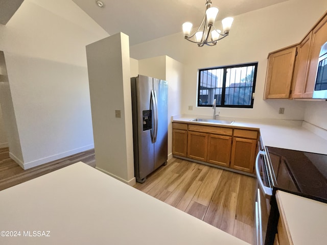 kitchen featuring pendant lighting, stainless steel appliances, light hardwood / wood-style flooring, sink, and a chandelier