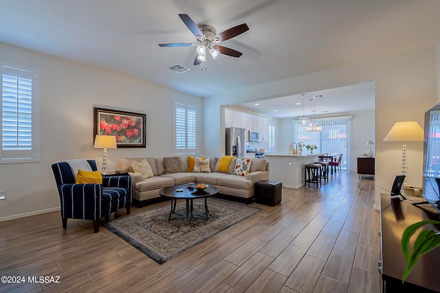 living room featuring sink, ceiling fan with notable chandelier, light hardwood / wood-style flooring, and a wealth of natural light