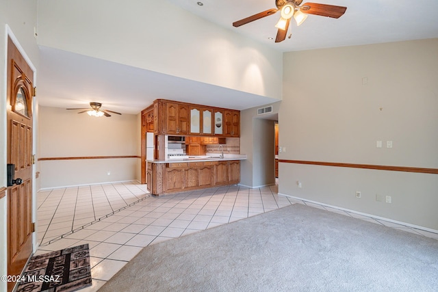 kitchen with light tile patterned floors, sink, ceiling fan, backsplash, and kitchen peninsula