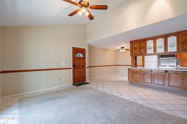 interior space with high vaulted ceiling, white refrigerator, stove, light colored carpet, and ceiling fan