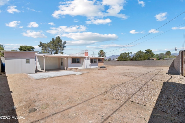 rear view of property with an outbuilding, a storage shed, a fenced backyard, a patio area, and a chimney