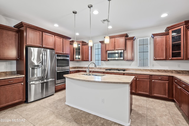 kitchen featuring a kitchen island with sink, sink, hanging light fixtures, light tile patterned flooring, and stainless steel appliances