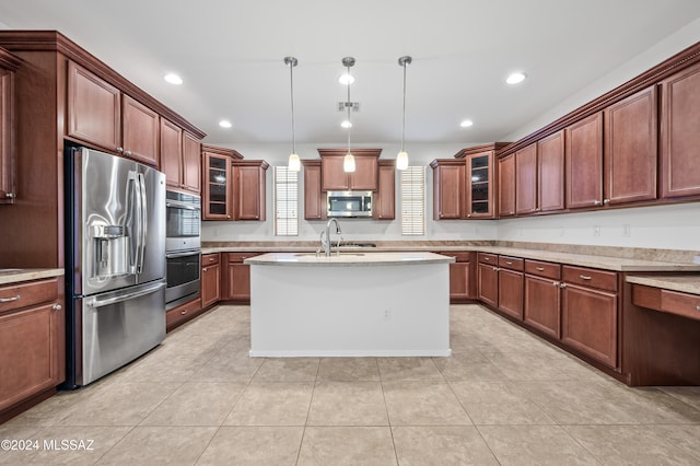 kitchen with appliances with stainless steel finishes, decorative light fixtures, light tile patterned floors, and an island with sink