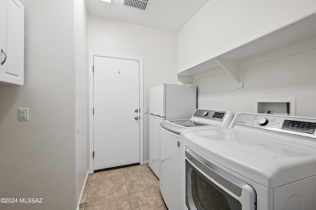 laundry area with cabinets, separate washer and dryer, and light tile patterned floors