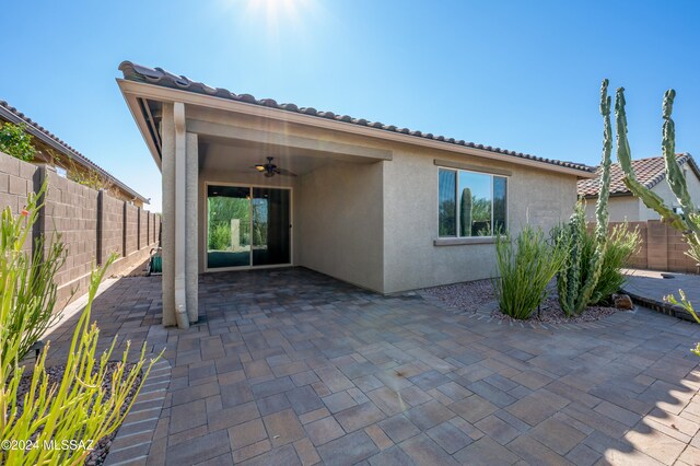 rear view of house featuring ceiling fan and a patio area