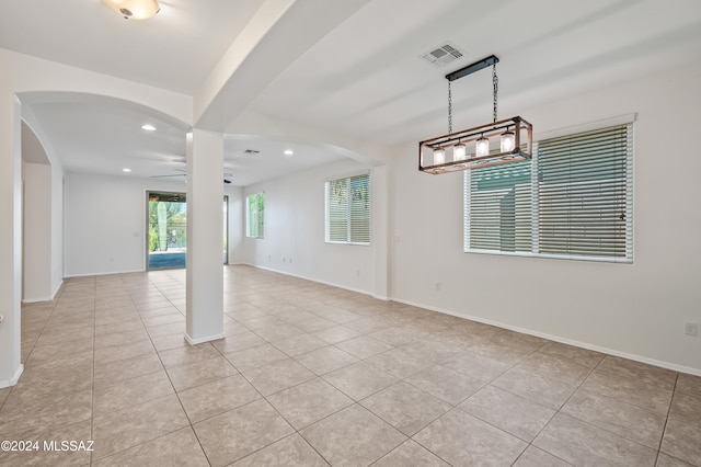 spare room with ceiling fan with notable chandelier and light tile patterned floors