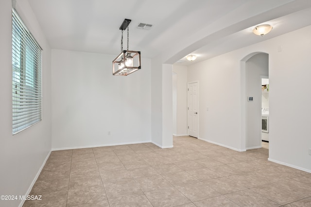 tiled spare room featuring a chandelier