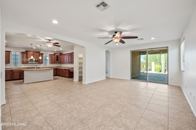 unfurnished living room with ceiling fan, light tile patterned floors, and sink