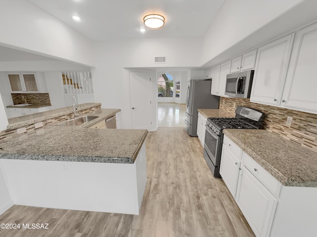 kitchen with sink, white cabinetry, light hardwood / wood-style flooring, appliances with stainless steel finishes, and backsplash