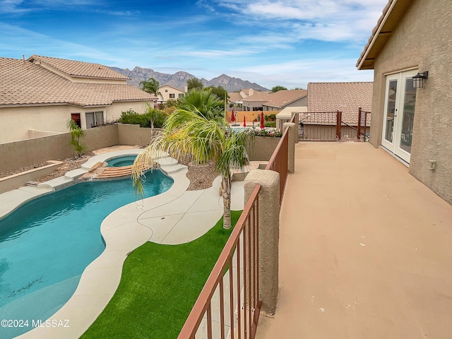 view of swimming pool featuring french doors, an in ground hot tub, a mountain view, and a patio