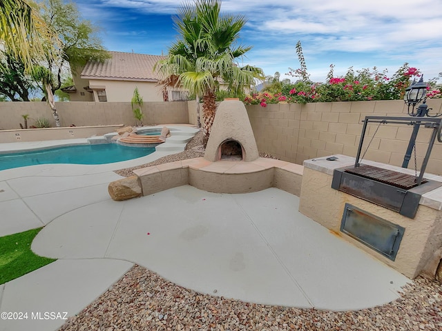 view of swimming pool with an outdoor fireplace, an in ground hot tub, and a patio area