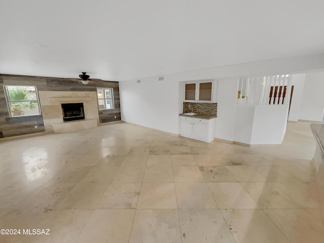 unfurnished living room featuring a high end fireplace and ceiling fan