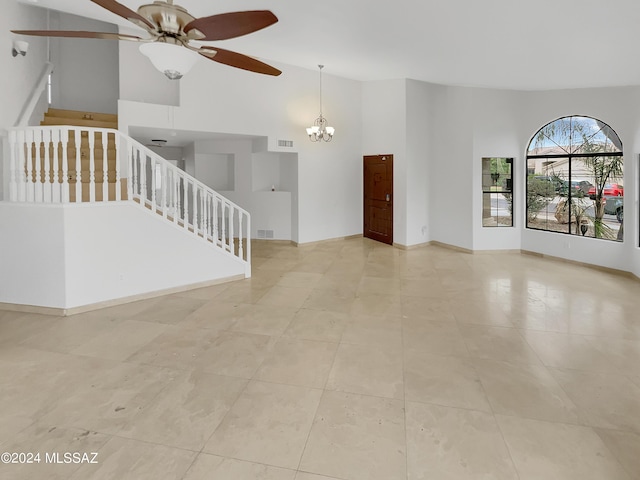 unfurnished living room with ceiling fan with notable chandelier and high vaulted ceiling